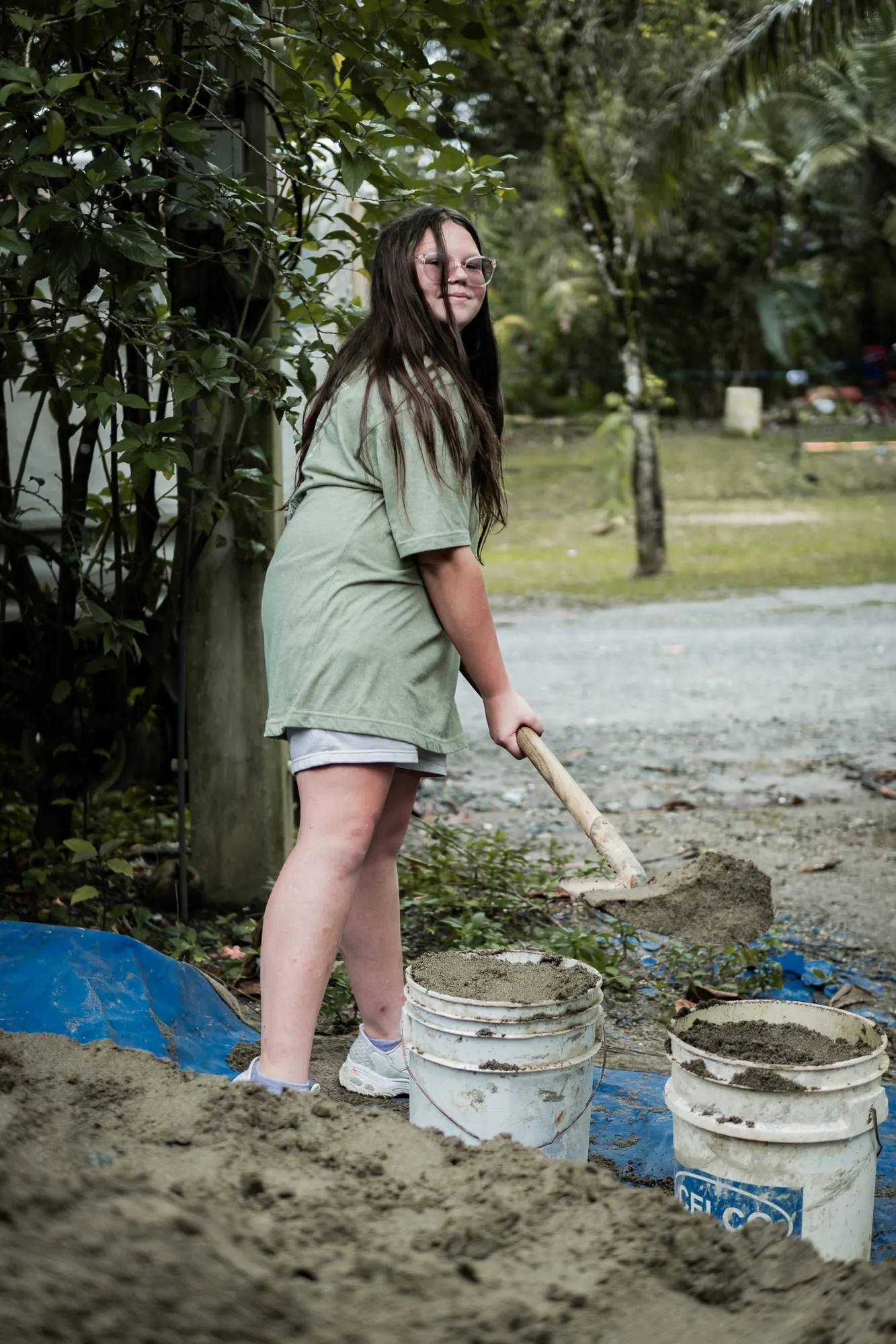 A volunteer helps prepare concrete for a community building project.