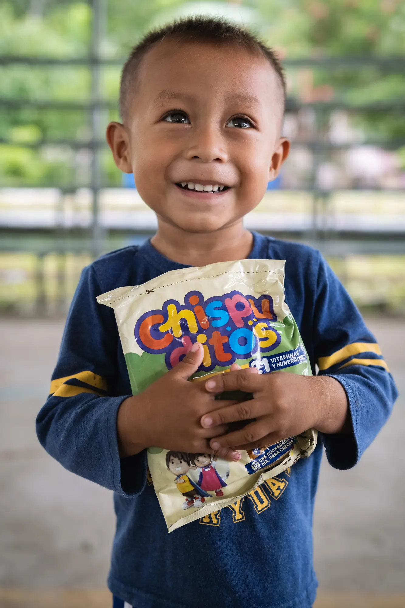 A young boy holds nutrition support provided through El Faro.