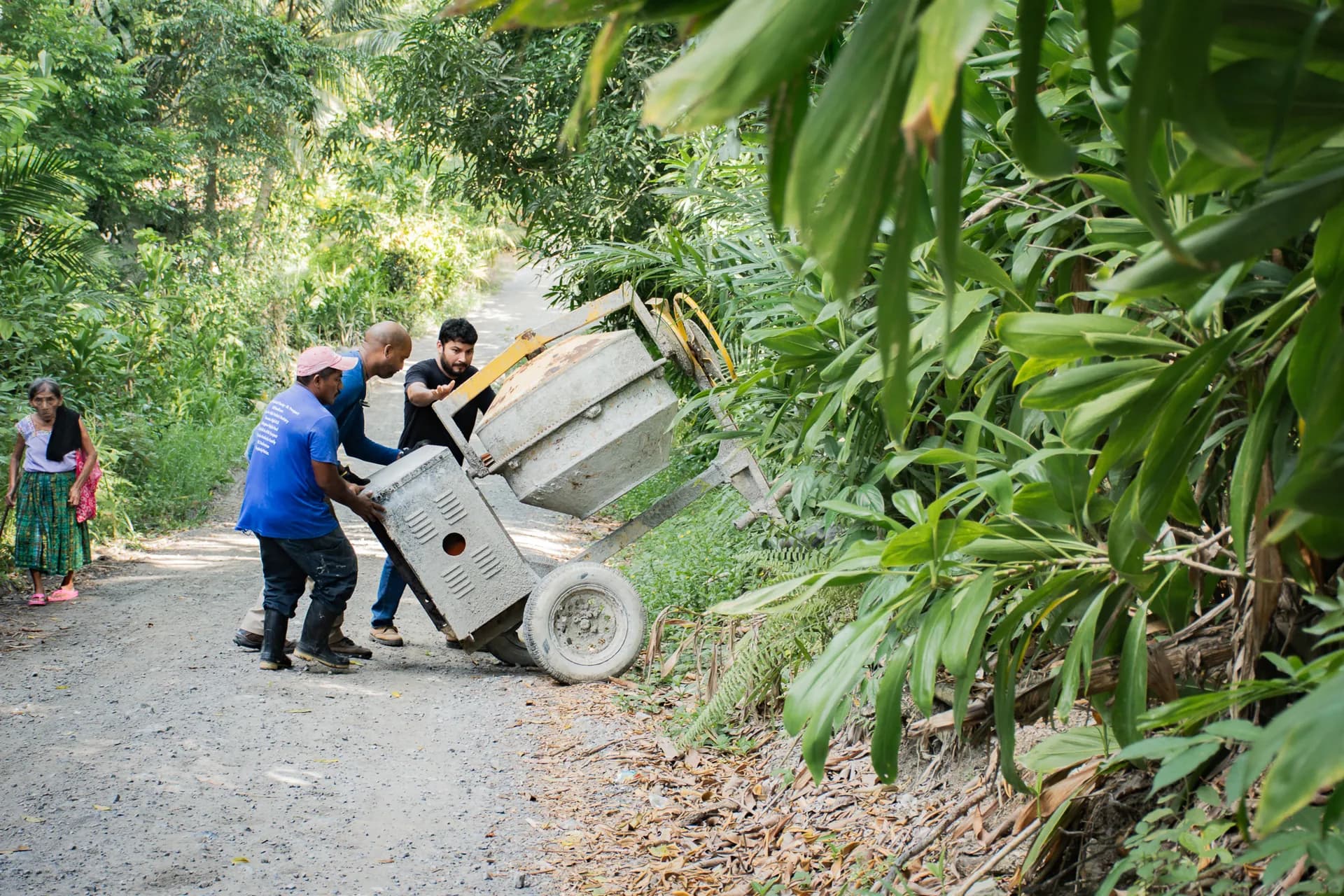Team members move project materials along a tropical path in Izabal, Guatemala.