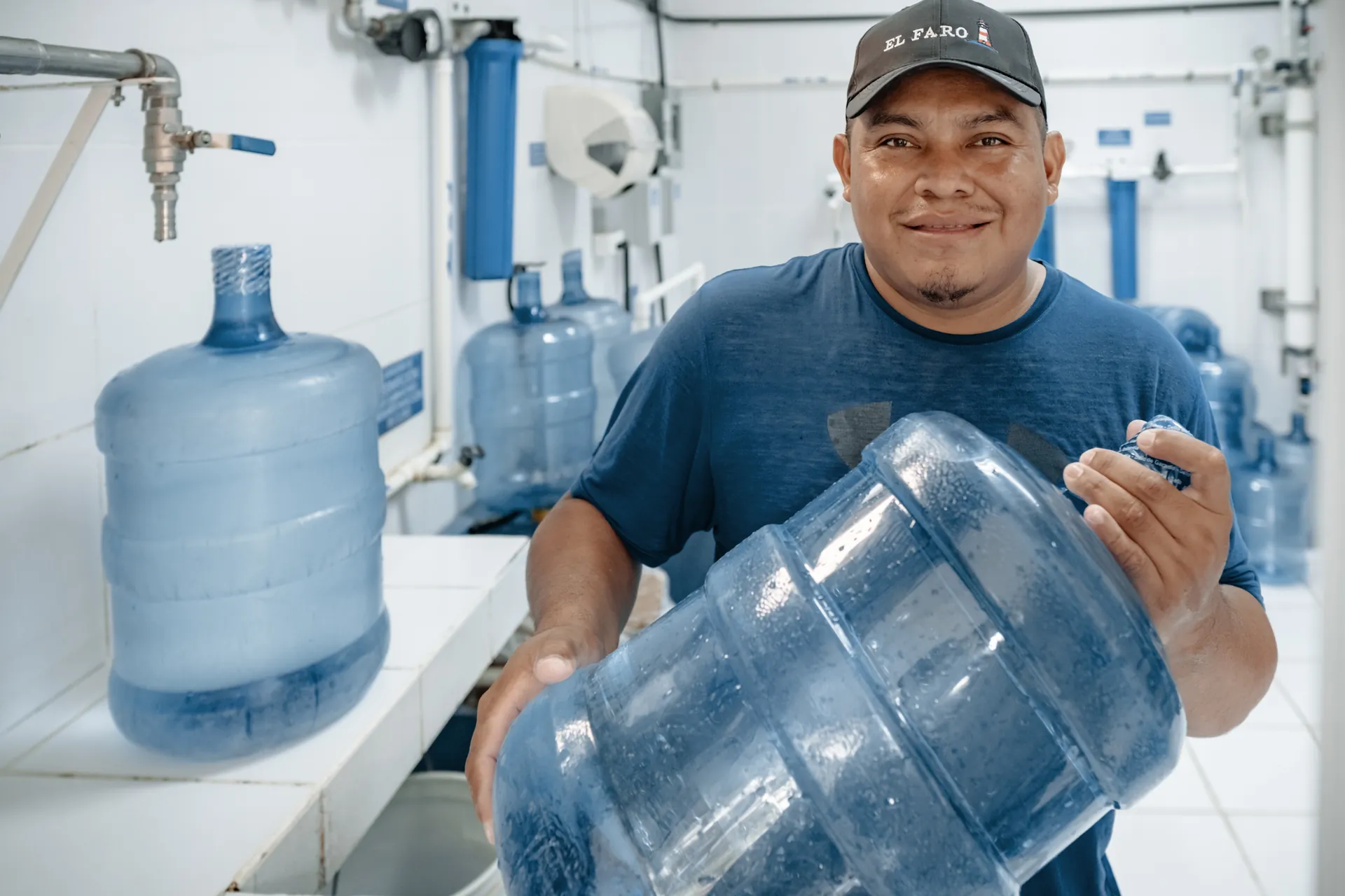 An El Faro team member holds clean-water bottles at a community purification facility.