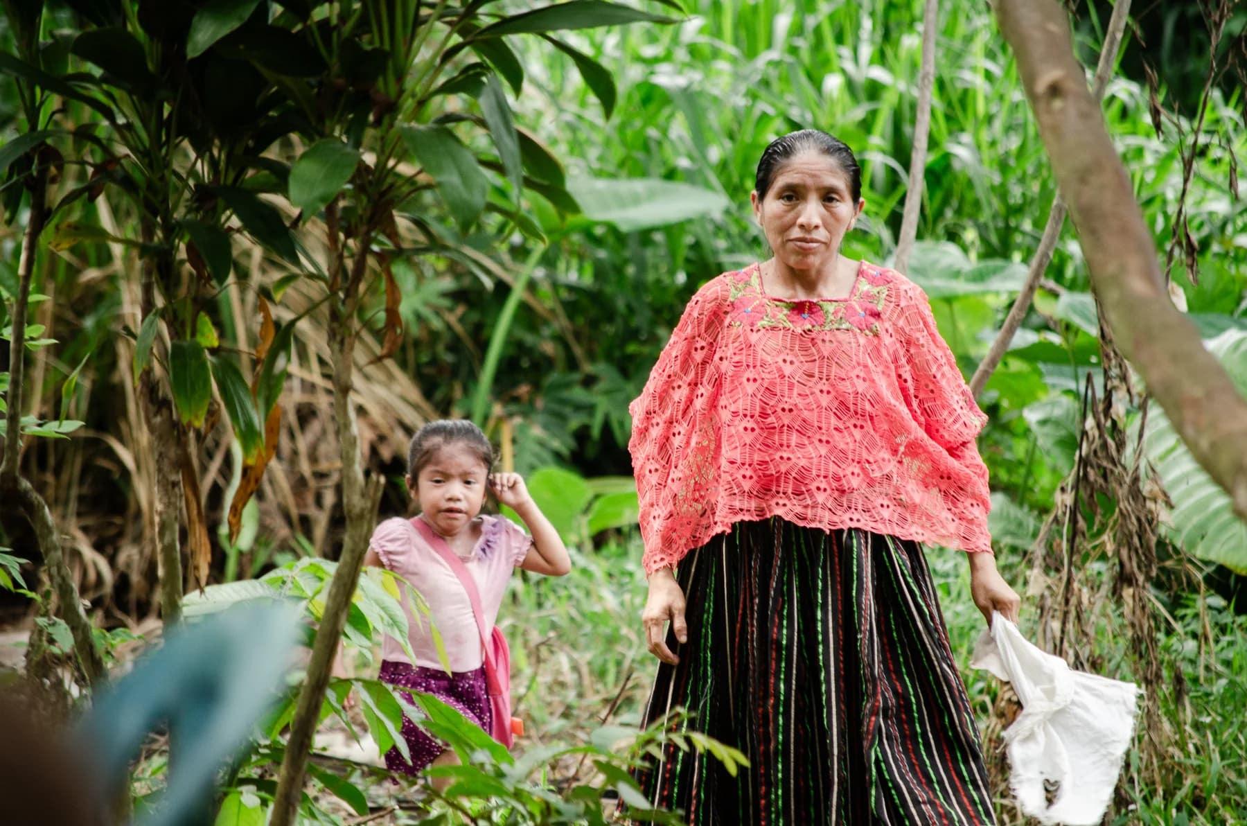 A woman and child walk along a tropical path.