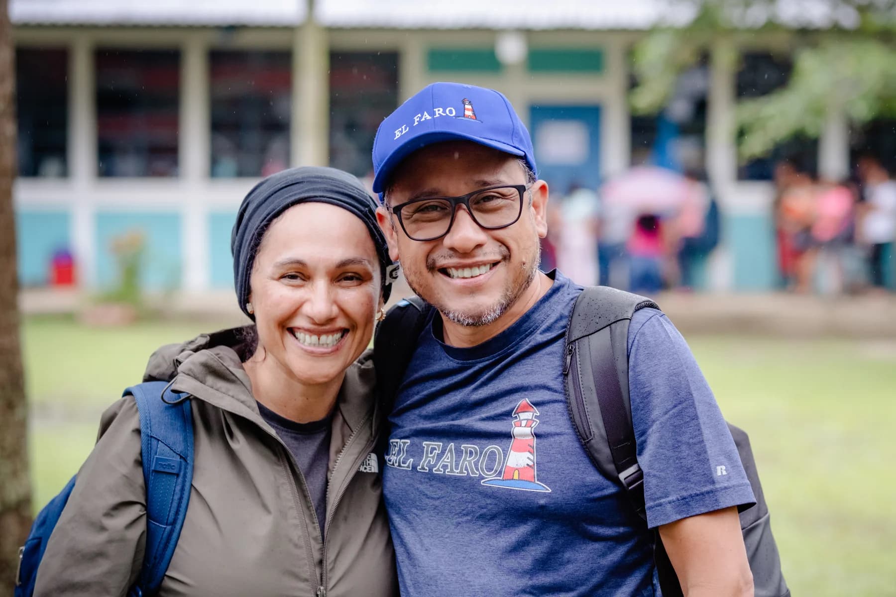 Two El Faro volunteers smile together outdoors.