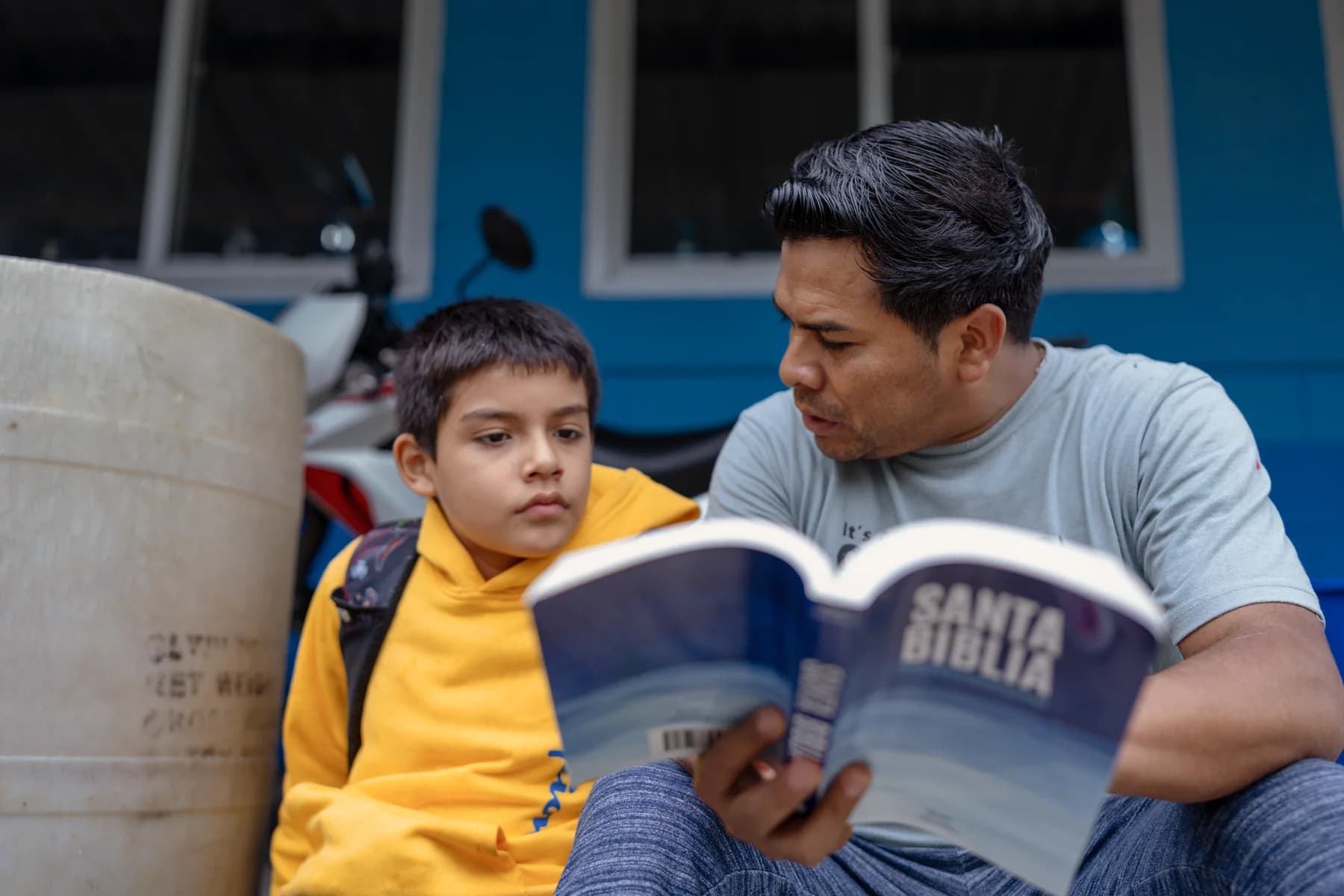 A man reads a Bible with a child at Iglesia Nueva Vida.