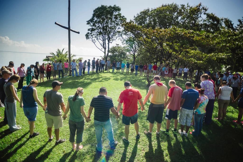 A group joins hands near the campus cross.